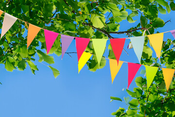 Colorful pennant string decoration against a tree and the summer sky