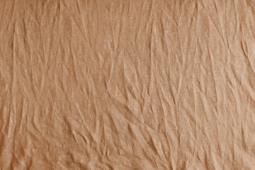 Wrinkled, crumpled brown fabric texture background. Wrinkled and creased abstract backdrop of cotton jersey textile, wallpaper with copy space, top view.