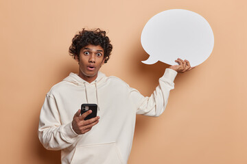 Need your input here. Stunned curly haired Hindu man appears startled as he frantically scrolls...