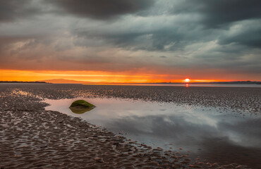 Moody dramatic skies and sunset reflections over Bowness on Solway Cumbria north east England UK