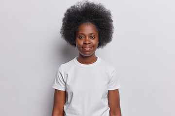 Close up horizontal portrait of young happy African woman with short curly black hair smiling isolalted in centre in white background standing still putting hands down. People lifestyle concept