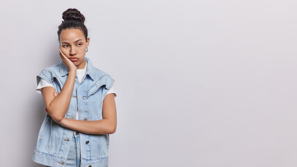 Horizontal shot of displeased Latin woman has sad and dejected expression looks away her eyes...
