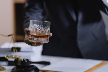 Law holding a glass of whiskey at desk, justice and law, attorney, court judge, concept.