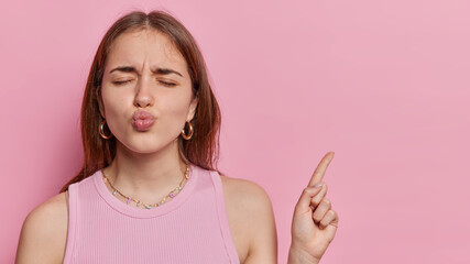 Studio portrait of young fit pretty European woman with closed eyes and protruded lips wearing...
