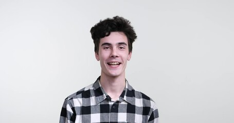 A charismatic curly-haired Caucasian man standing against a pristine white background. With a warm smile on his face, he nods his head in a resolute gesture, uttering a firm yes