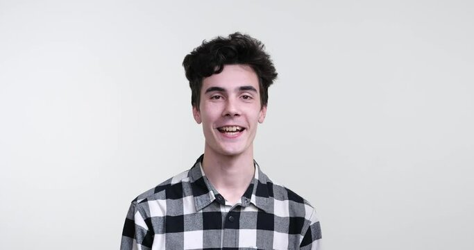 A charismatic curly-haired Caucasian man standing against a pristine white background. With a warm smile on his face, he nods his head in a resolute gesture, uttering a firm yes