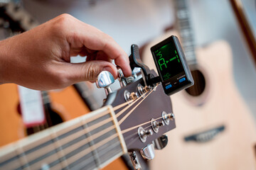 Young musician tuning a classical guitar in a guitar shop