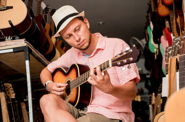 Young musician testing classical guitar in a guitar shop