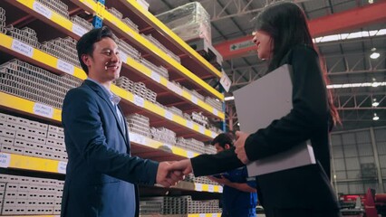 Business man manager leader and woman assistant holding document file and shaking hands after reach an agreement together at metal factory.Factory and Warehouse concept. - Powered by Adobe