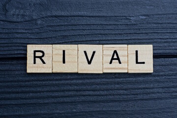  text the word rival from brown wooden small letters on a black table