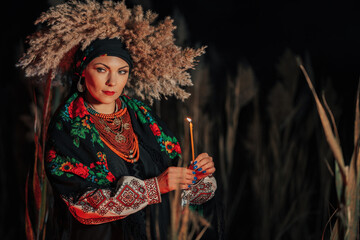 Mysterious ukrainian woman with candle, she in traditional costume outdoors