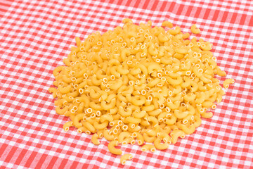 Scattered Uncooked Chifferi Rigati Pasta on Red Checkered Towel. Fat and Unhealthy Food. A Heap of Classic Dry Macaroni. Italian Culture and Cuisine. Raw Pasta