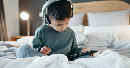 Boy, kid and tablet with headphones in bedroom for online games, watching movies and play educational app at night. Child, digital technology and listening to multimedia, music and streaming cartoon - Powered by Adobe
