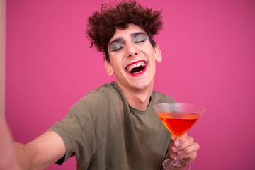 Party and delicious cocktails. Funny drag queen posing in the studio on a pink background.