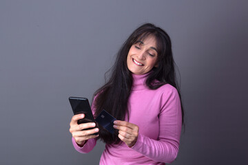Naklejka premium elegant woman in turtleneck sweater, buying with card and mobile