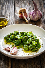 Broad beans with garlic and dill on wooden table
