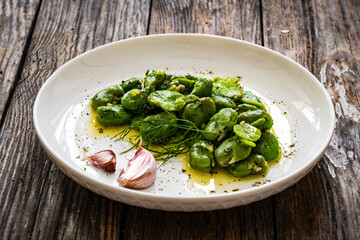 Broad beans with garlic and dill on wooden table
