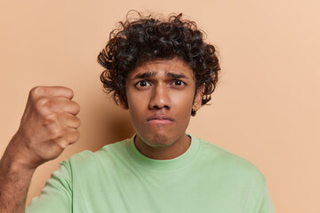 Angry discontent Hindu man with dark curly hair clenches fist expresses annoyance being outraged...