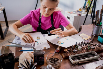 Young female jeweler making jewelry in workshop