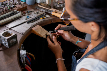Young faemale jeweler polishing jewelry in workshop - obrazy, fototapety, plakaty
