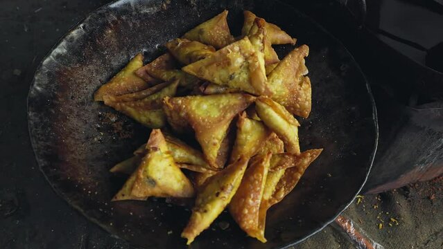 A closeup of freshly fried beef or vegetable samosa on a pan at a roadside shop