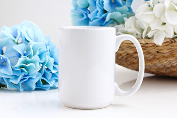 15 oz Mug mockup with blue and white flowers on a white table.