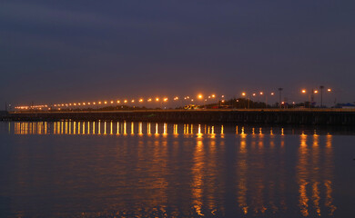 Fototapeta na wymiar Bridge with Lighting Reflections on the Sea at Night