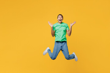 Fototapeta na wymiar Full body young man of African American ethnicity he wears casual clothes green t-shirt hat jump high look camera spread hands isolated on plain yellow background studio portrait. Lifestyle concept.