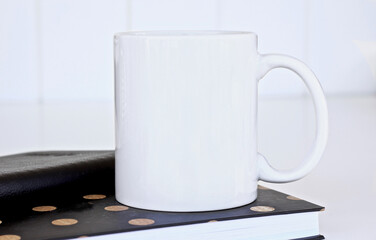 Mug mockup with black books on a white table.