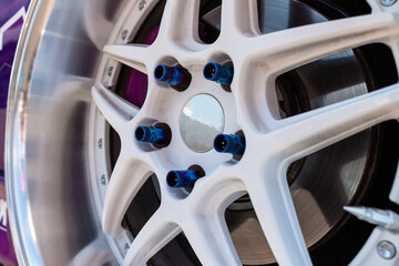 Close up of sport car wheel. Aluminum alloy wheel painted in white color. Car tuning. 