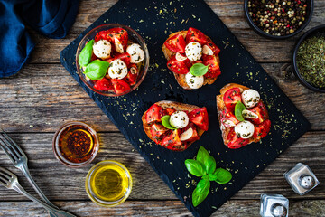 Tasty sandwiches - toasted bread with mozzarella balls cheese, tomatoes and basil leaves on wooden table
