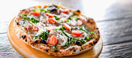 Pizza Italiana served with ham, cheese, tomatoes and rucola