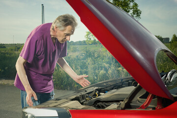 Pensioner checking state of his car with smoking engine