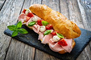 Big sandwich with mortadella with pistachios and mozzarella cheese on wooden table
 - obrazy, fototapety, plakaty