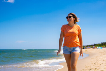 Beautiful woman walking on sunny beach
