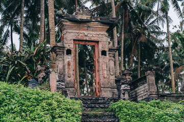Fototapeta na wymiar Stone temple gates in tropical jungle. Ancient ruins surrounded with exotic palms trees