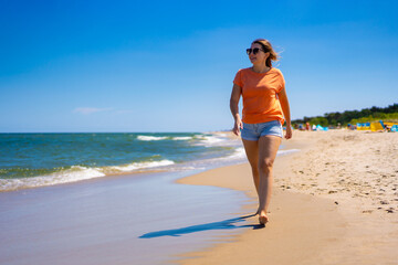 Beautiful woman walking on sunny beach
