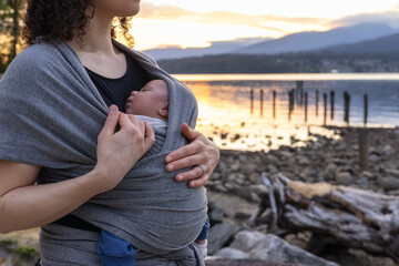 Small newborn baby boy with his mother at a park. Sunset.
