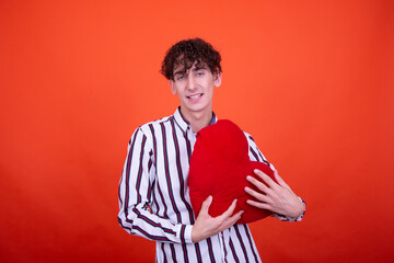 Young attractive emotional guy posing in the studio on an orange background.