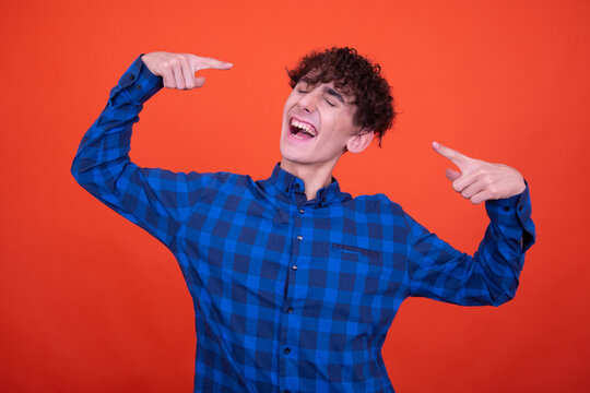 Young Attractive Emotional Guy Posing In The Studio On An Orange Background.