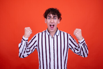 Young attractive emotional guy posing in the studio on an orange background.