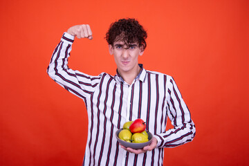 Young attractive emotional guy posing in the studio on an orange background.
