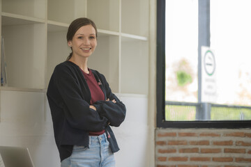 Portrait of cheerful smiling woman standing with arms crossed.