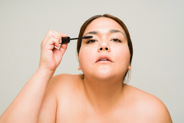 Hispanic big woman on a beauty concept putting on mascara