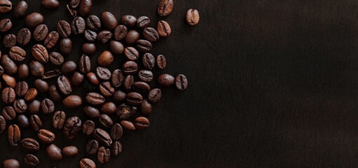 Roasted coffee beans on a wooden dark table, top view. Background of fragrant brown coffee beans...