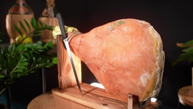 Fat cured ham on wooden stand with knife for slicing, traditional jamon leg of mediterranean cuisine, Italian food and antipasto concept
