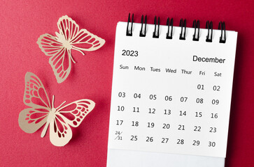 A December 2023 desk calendar for the organizer to plan and reminder with paer butterfly on red background.
