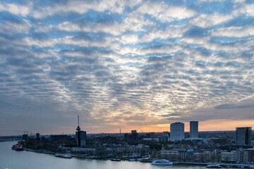 Panoramic high level view during sunset over the Maas river and part of the city of Rotterdam, the Netherlands with cloudscape of cirrocumulus clouds coloring orange and yellow