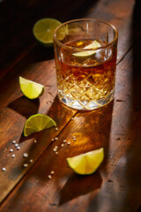 Summer drink, whiskey, tequila or cognac, lemonade, alcoholic or non-alcoholic cocktail with limes and salt on a wooden table