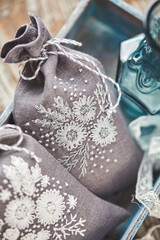 Sachets with embroidery filled with lavender on wooden background